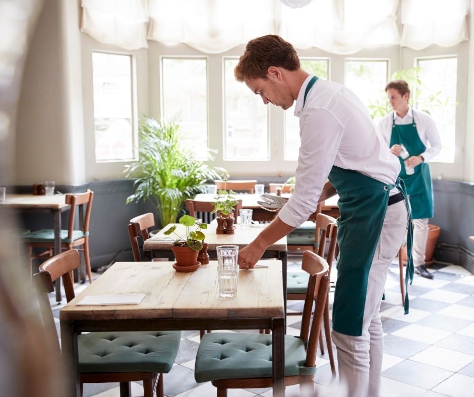 Waiters setting tables in a bright restaurant